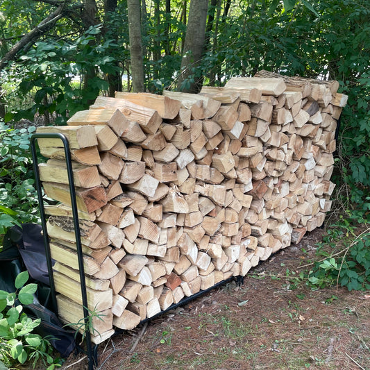 Face Cord of Firewood Stacked in a Rack with Shrubbery in the Background