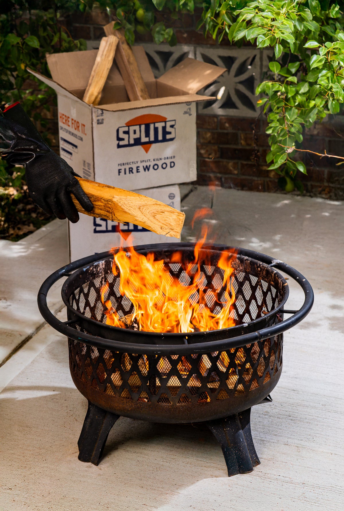 Adding SPLITS kiln-dried firewood to a backyard fire pit