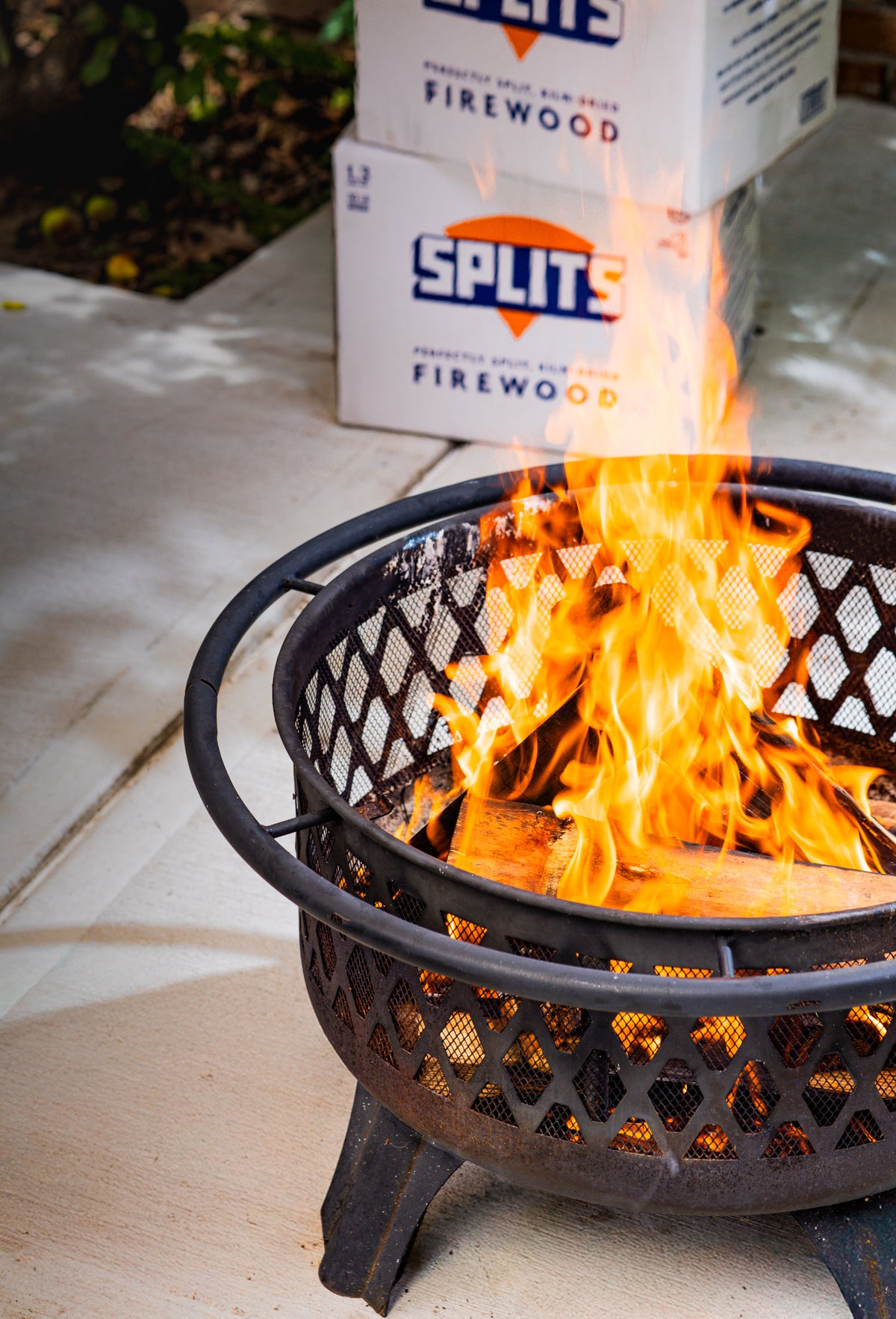 Adding SPLITS kiln-dried firewood to a backyard fire pit