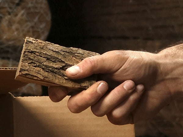 Hand holding a three-inch smoking wood chunk