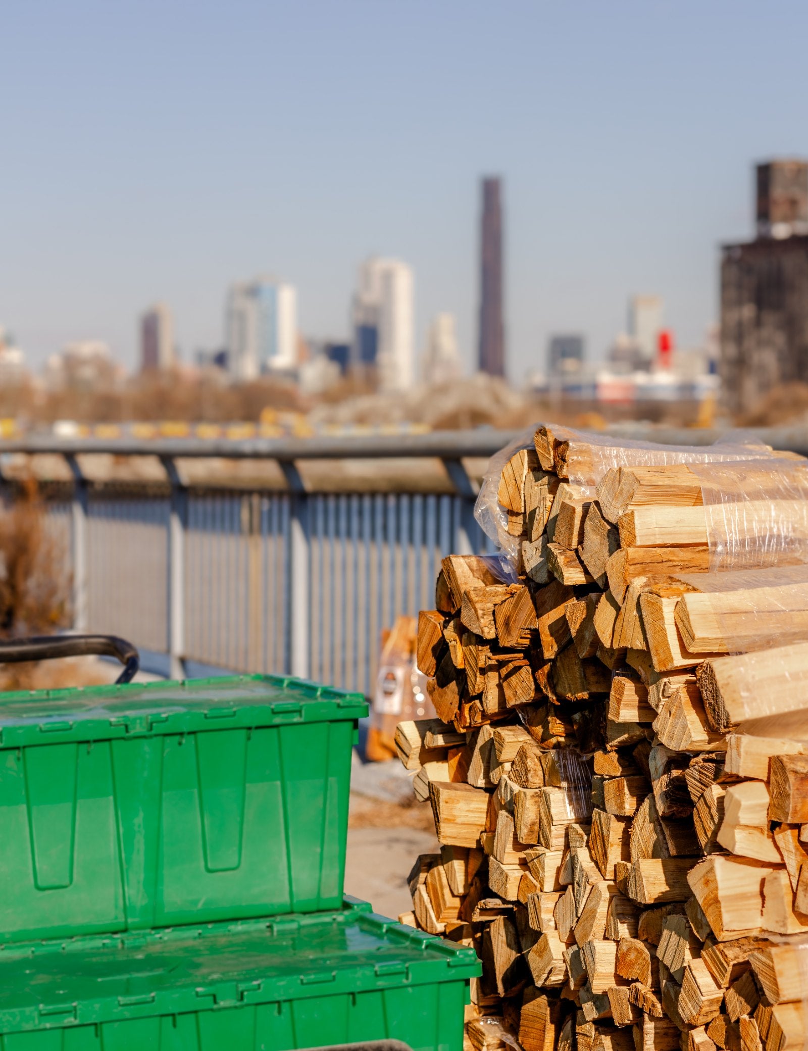 Kiln-dried firewood stacked at Woodbourne's Long Island City Warehouse with the New York City skyline behind