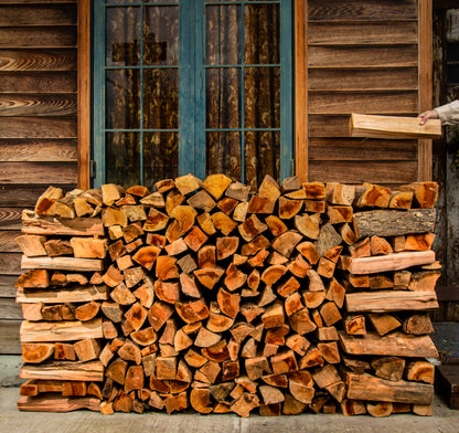 A split of kiln dried firewood being placed on a stacked quarter cord